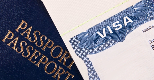 a stack of papers with a visa card and passport on top
