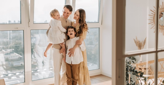 a woman, man, and two young children smiling while standing in a living room