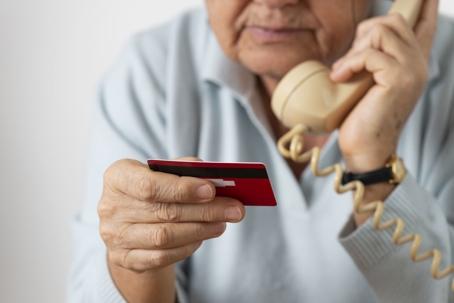 elderly man on phone giving payment with credit card