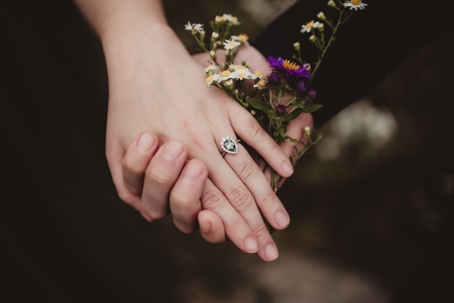 couple holding hands showing wedding ring